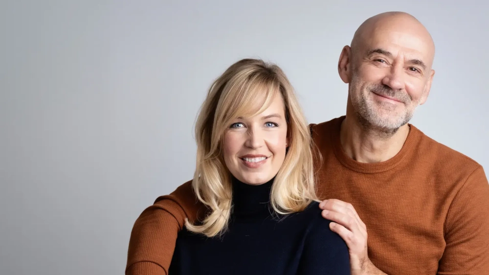 A smiling couple in their fifties, his hand on her shoulder