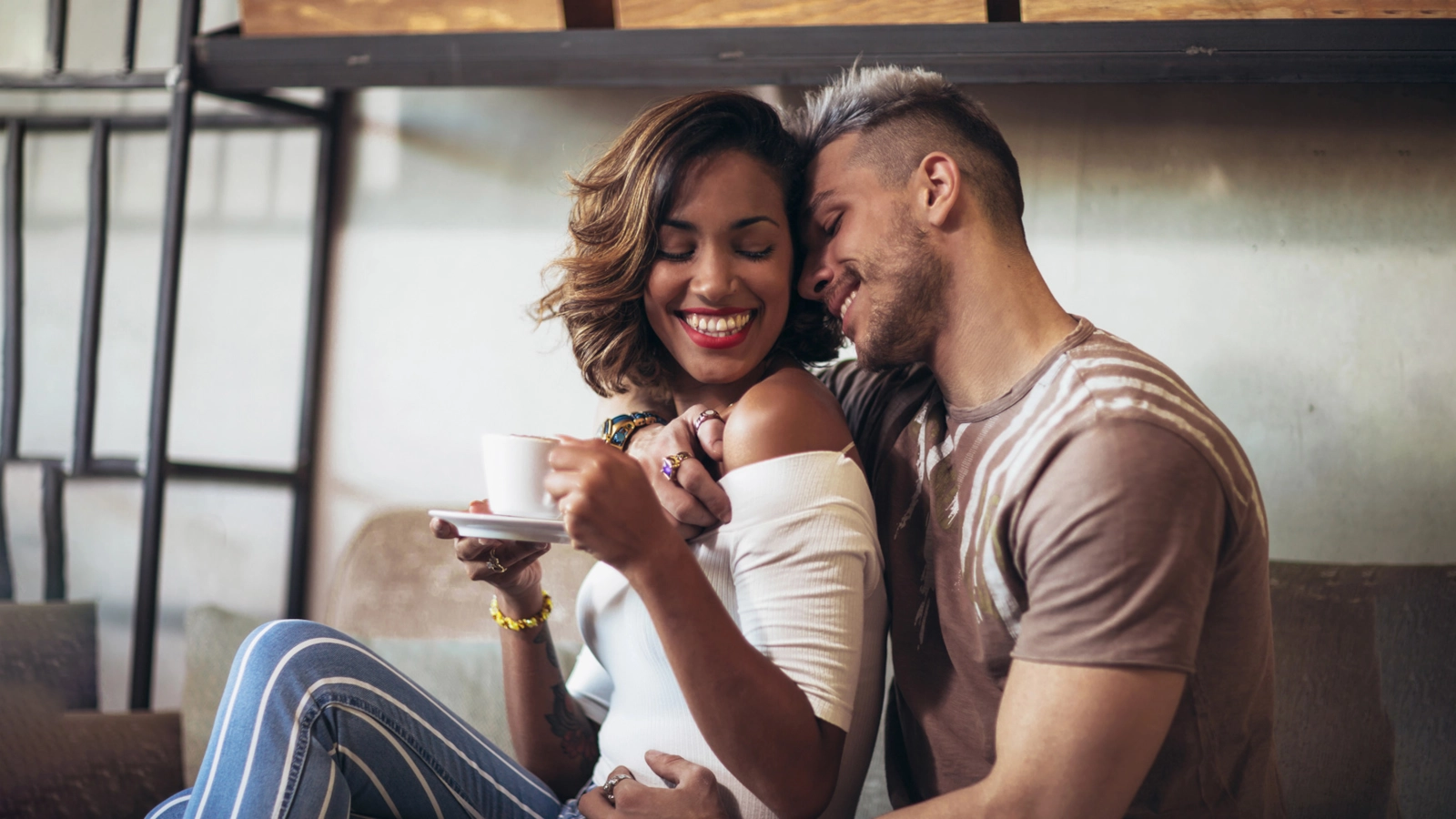 A couple laughing together over coffee at a cafe table