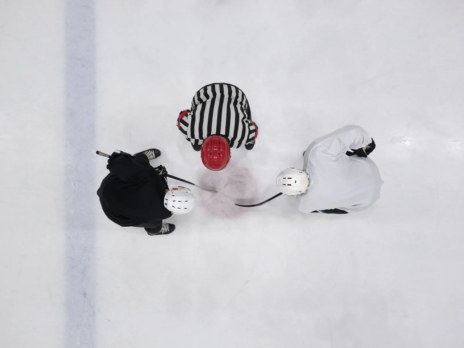 Vue d'en haut d'un arbitre qui laisse tomber la rondelle entre deux joueurs