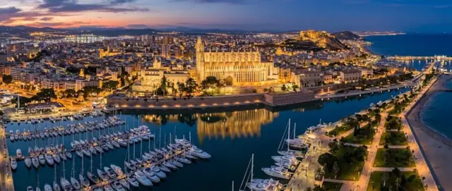 Catedral de Palma iluminada al anochecer sobre el puerto deportivo y el paseo marítimo
