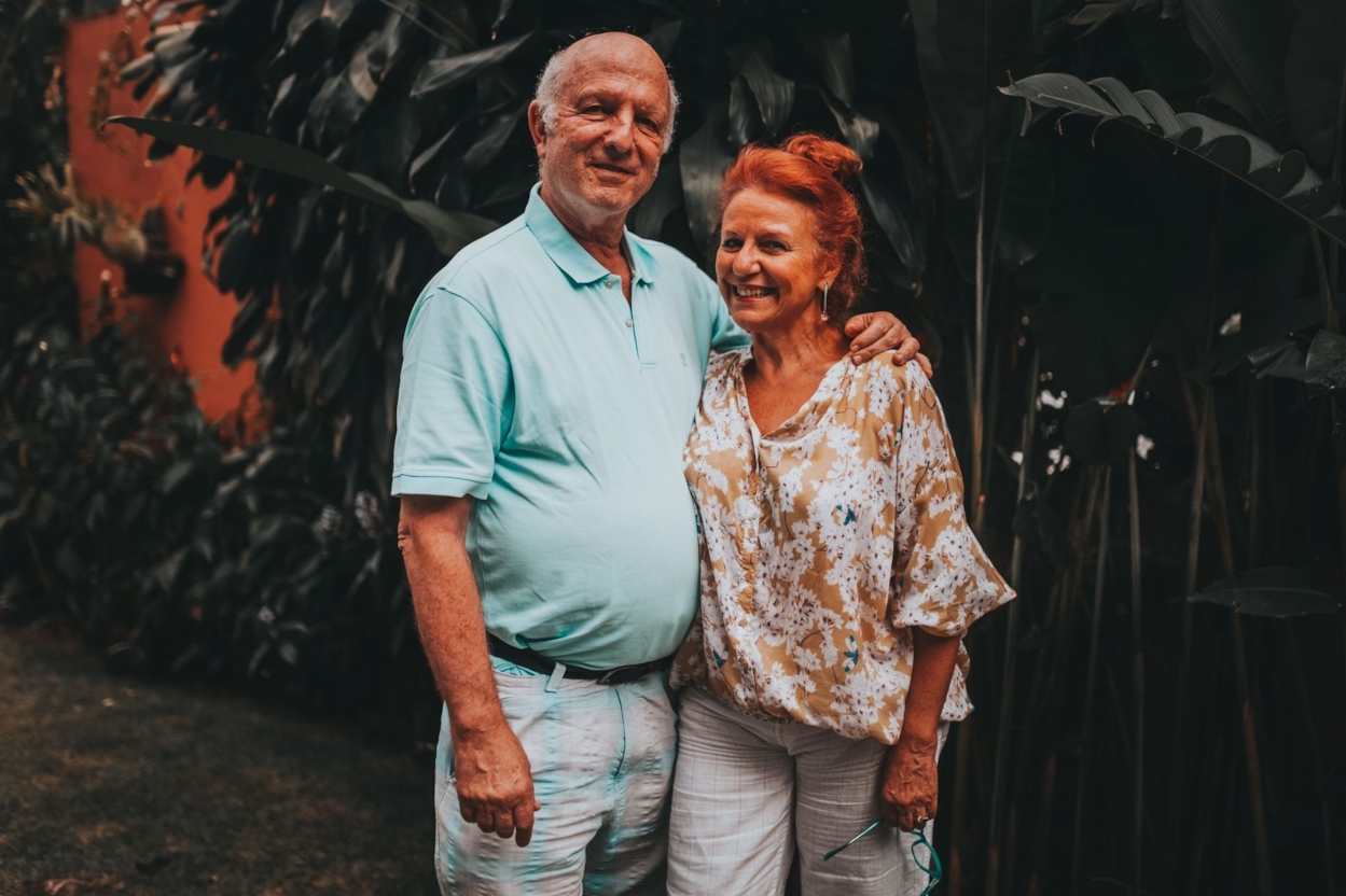 Smiling mature couple standing arm in arm outdoors