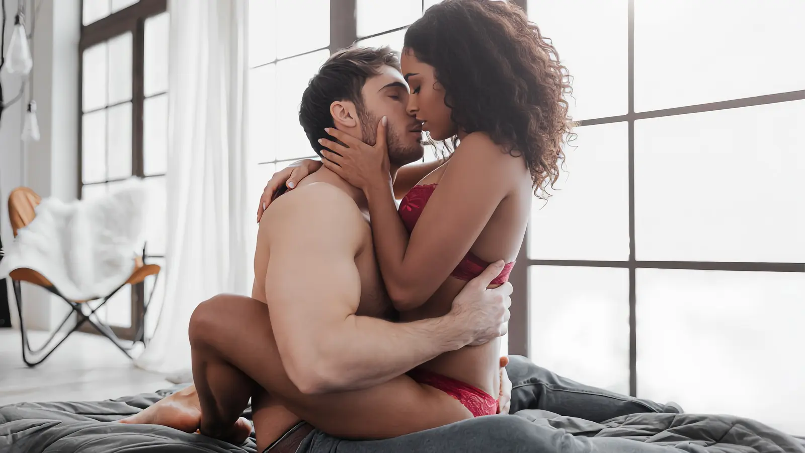A man and a woman with curly hair kissing in front of tall windows, interracial dating in Los Angeles