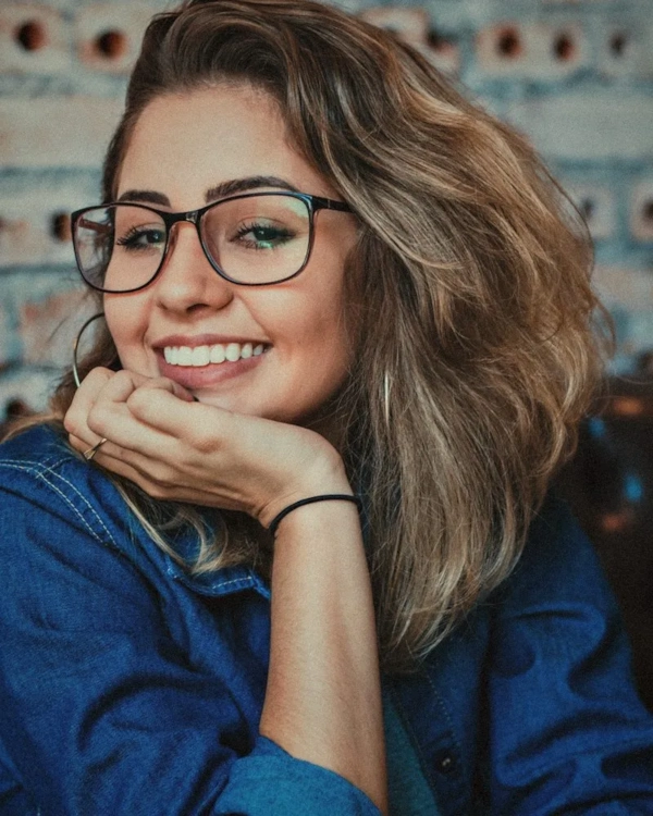 Smiling woman in glasses resting her chin on her hand