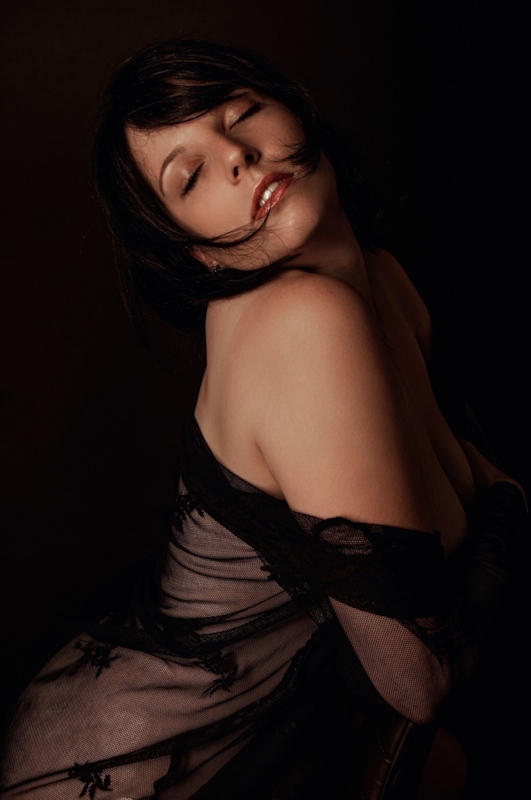 Illustrative stock close portrait of a dark-haired woman with sheer black lace at her shoulder