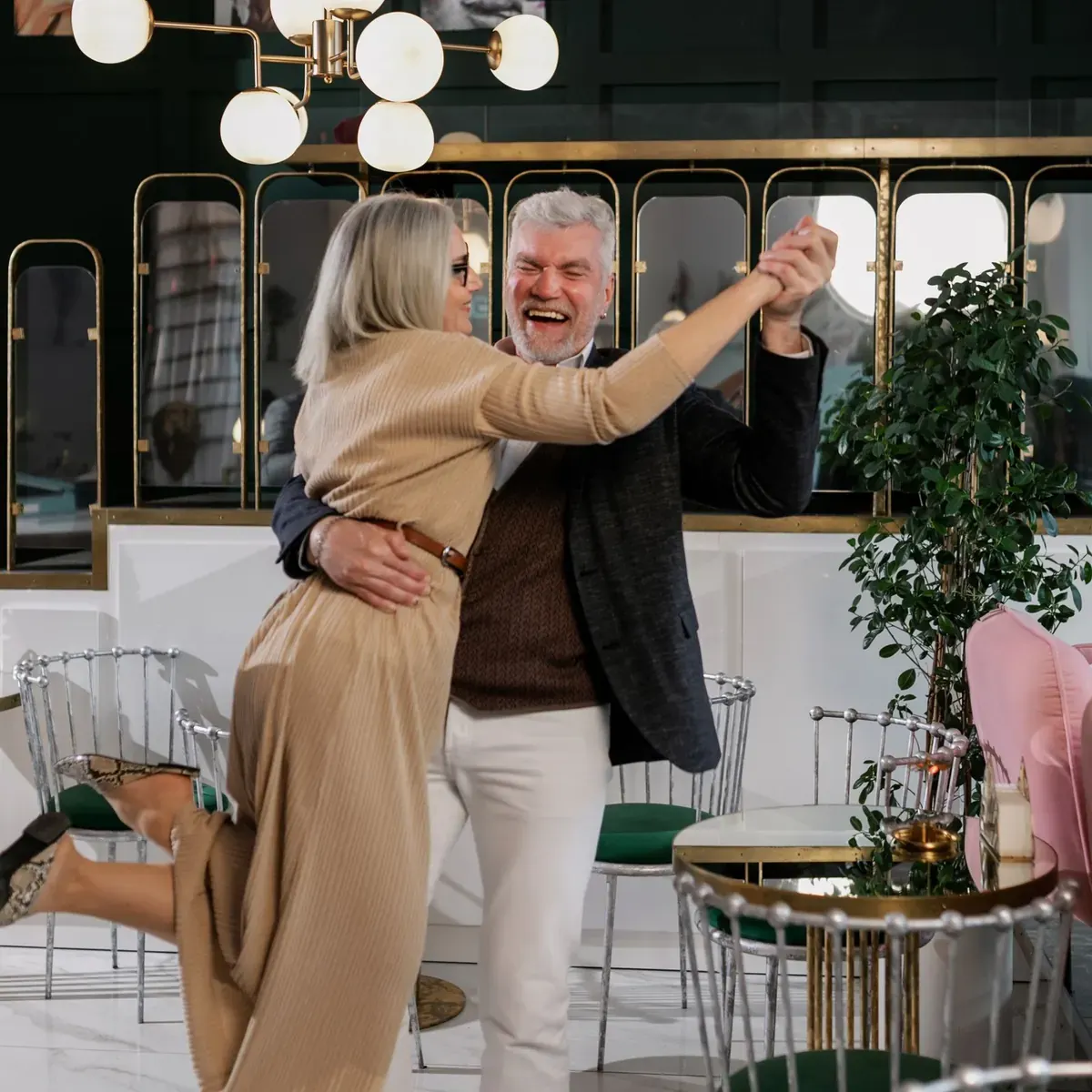 A smiling couple dancing together in a stylish bar with globe lights