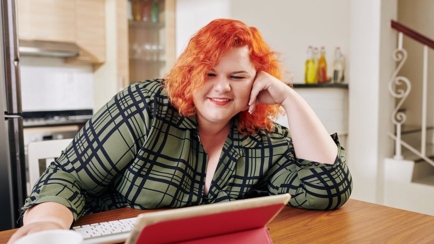A woman relaxing at her kitchen table with a tablet