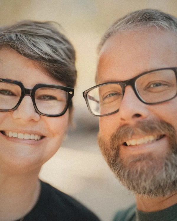 Smiling couple, both wearing glasses, cheek to cheek
