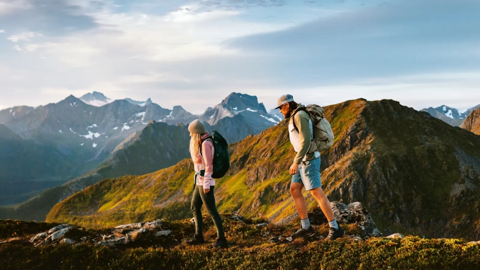 Two hikers walking along a mountain ridge at golden hour