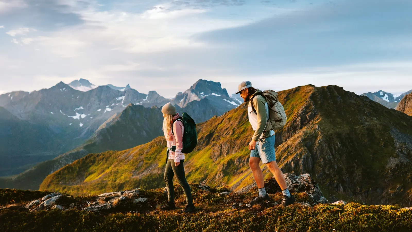 Two hikers walking along a mountain ridge at golden hour