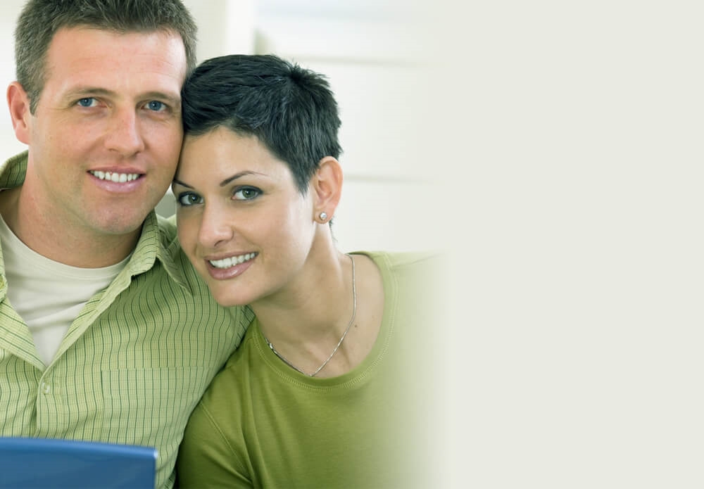 A smiling couple sitting close together at home