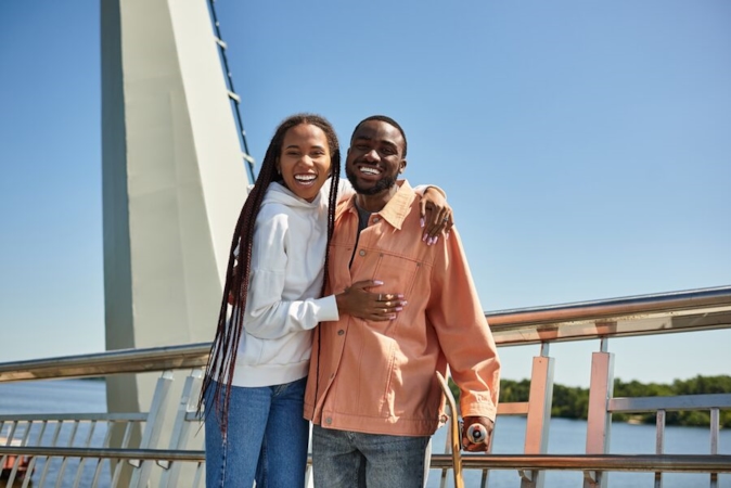 Happy couple laughing together on a bridge on a sunny day