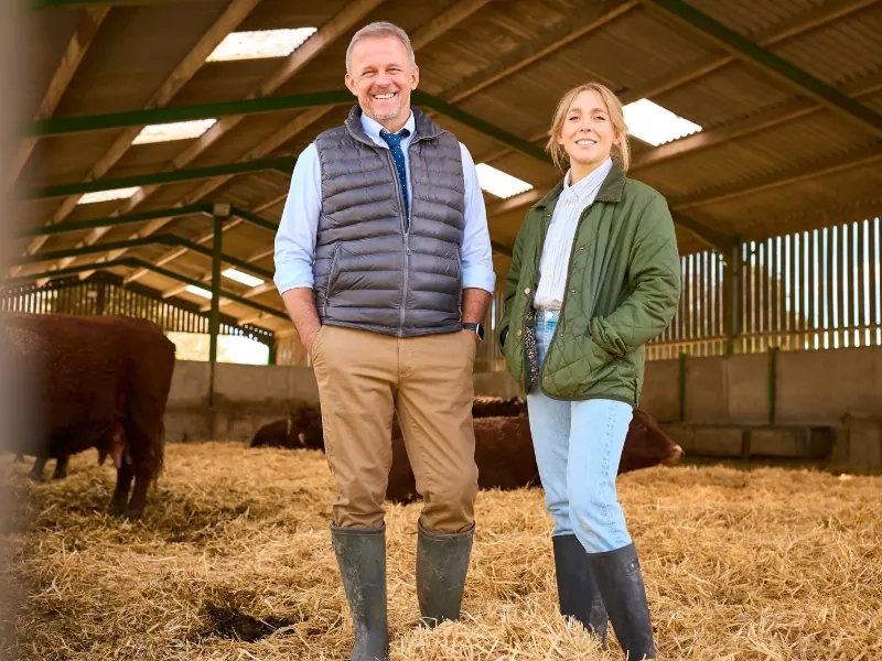 A couple standing side by side in a cattle barn in their working clothes