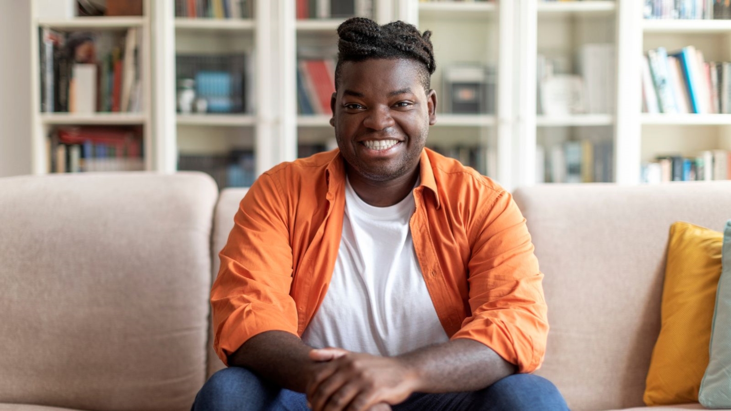 A man smiling warmly while sitting on his sofa at home