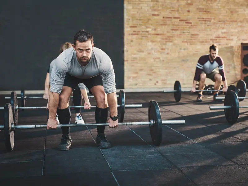 A group of men and women lifting barbells together in a strength class