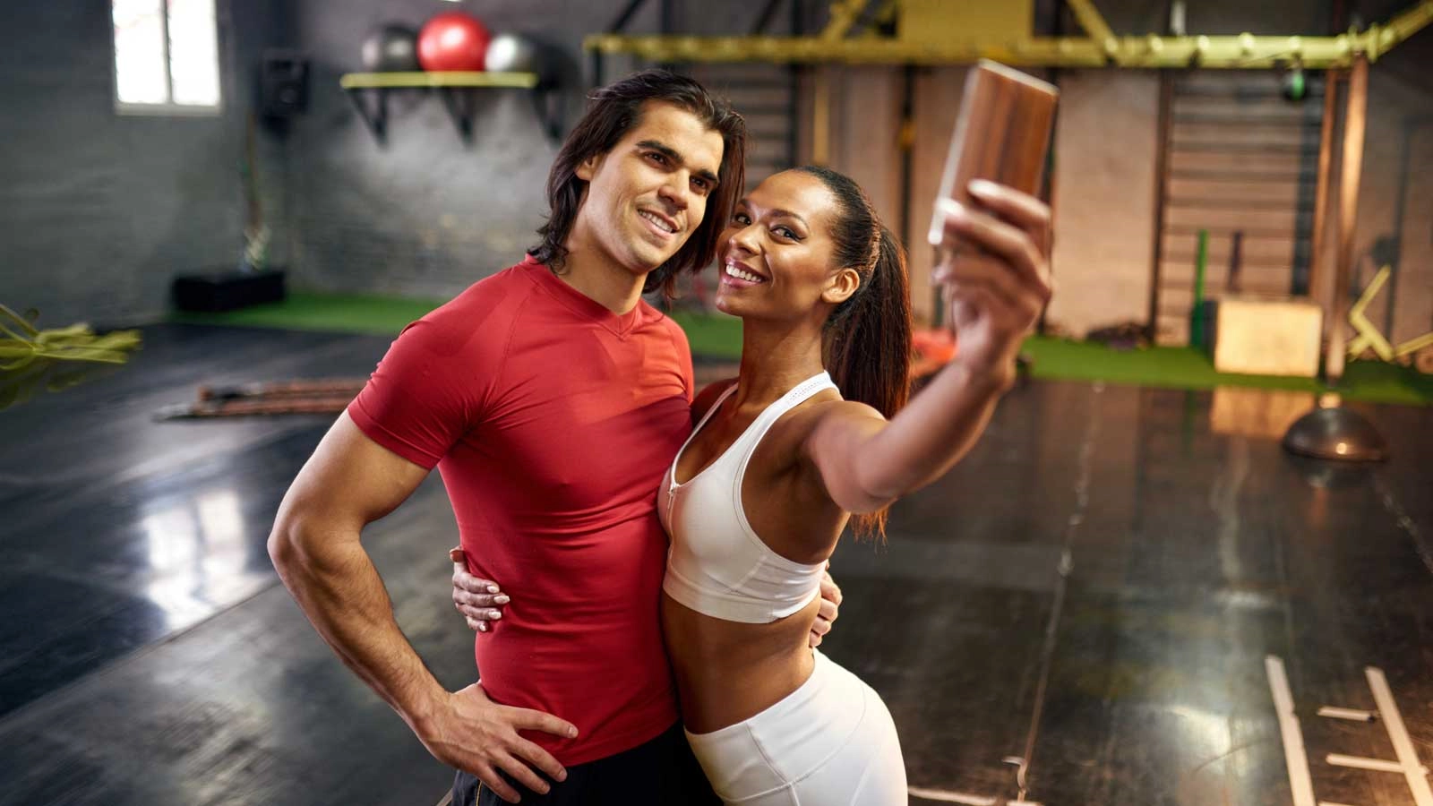 A smiling couple taking a selfie together after a workout at a Georgia gym