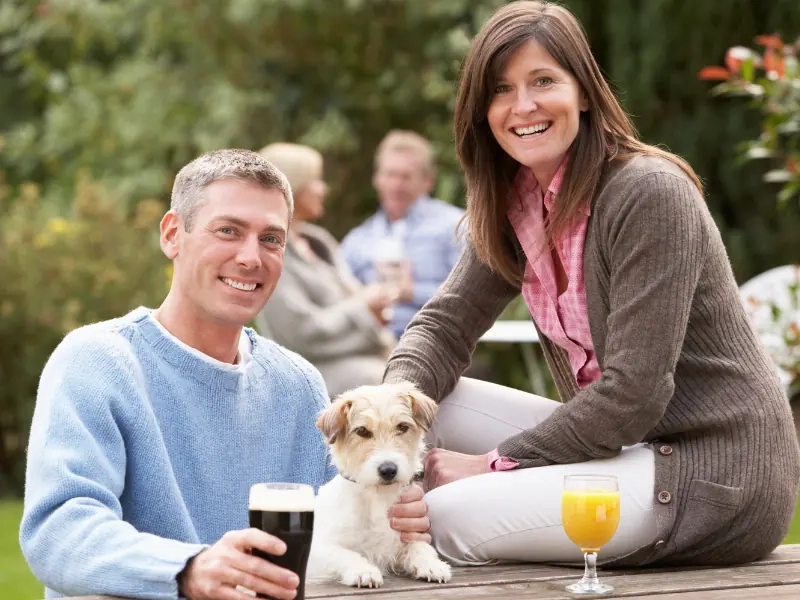 A couple sitting outside a pub with their dog