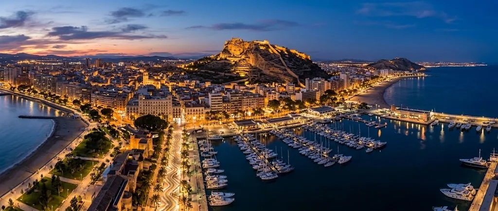 Vista aérea de Alicante al anochecer con el puerto y el castillo de Santa Bárbara