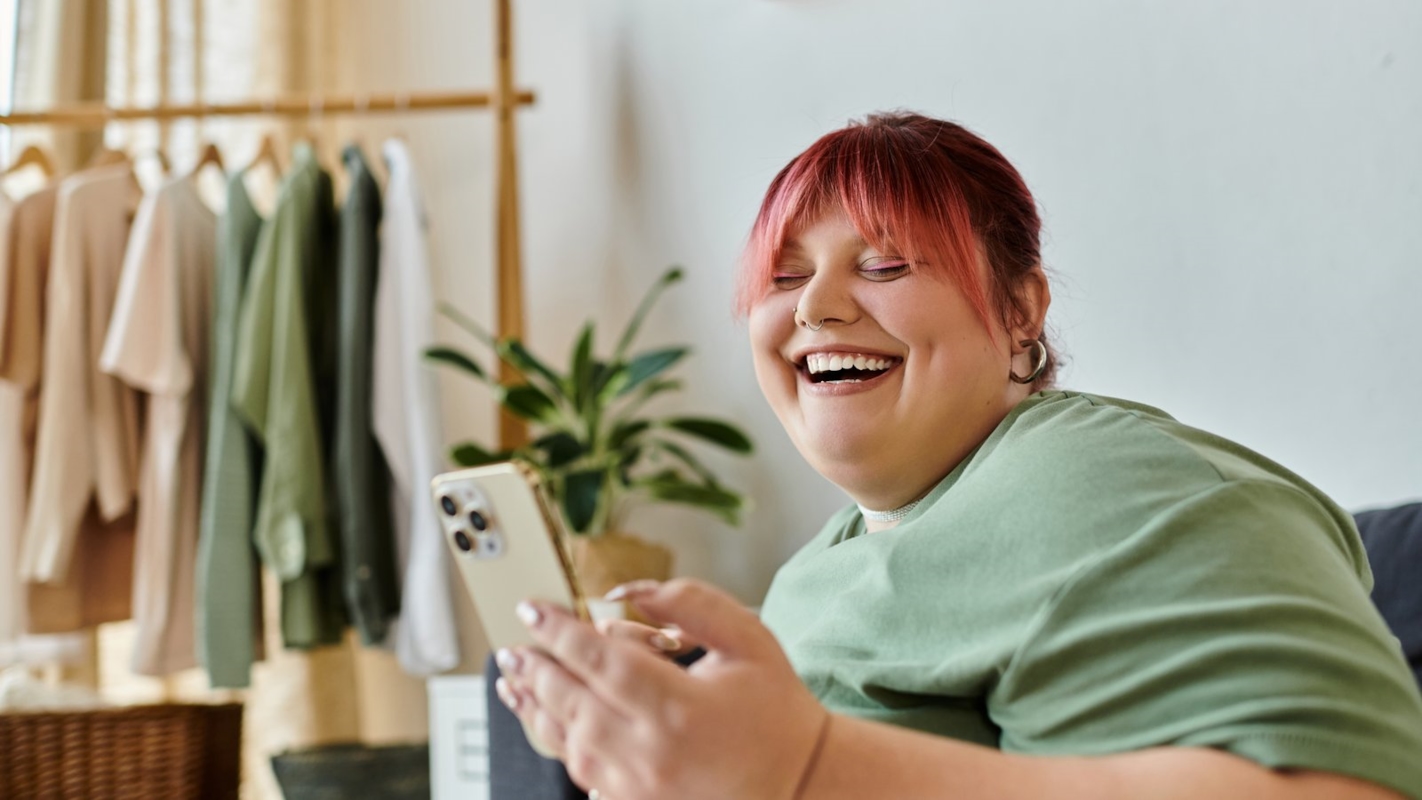 A woman laughing while looking at her phone