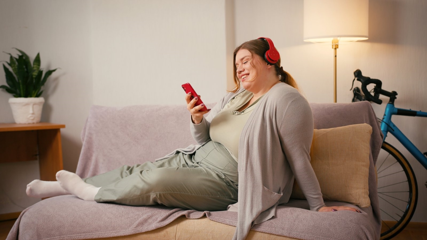 A woman relaxing on the sofa at home, listening to music on headphones