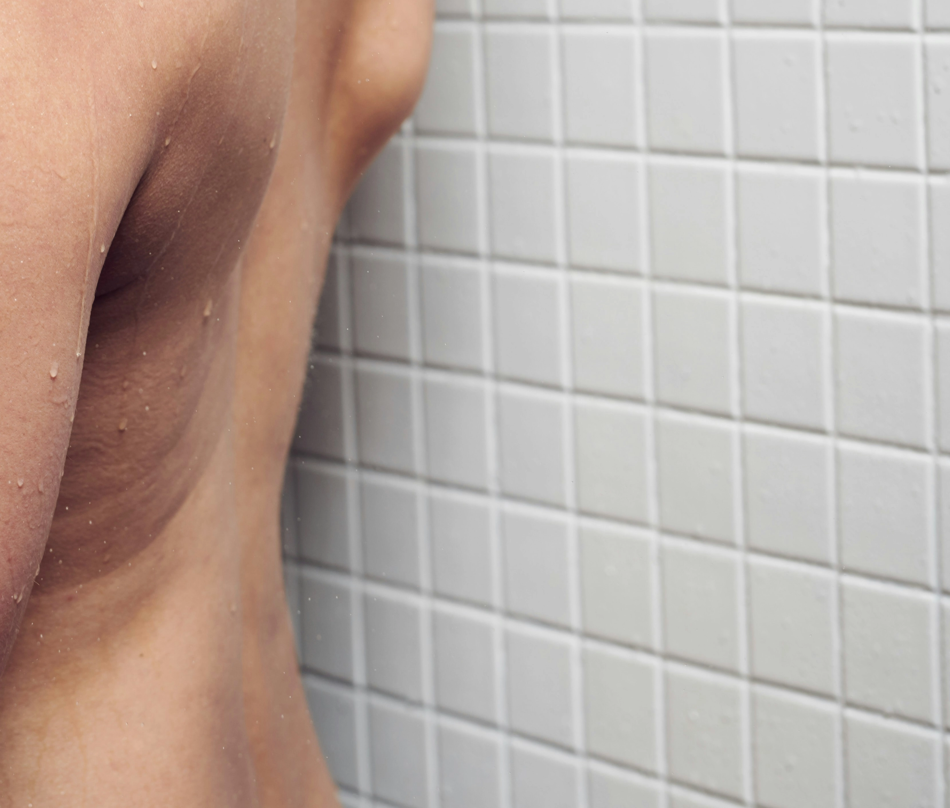 Pareja en la ducha, desnuda, con el agua corriendo, creando un ambiente sensual y de privacidad.