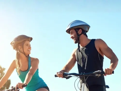 A couple on mountain bikes smiling at each other under a clear blue sky
