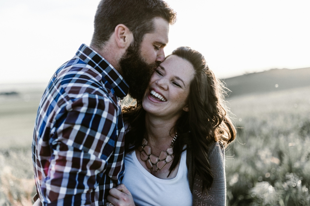 A couple embracing warmly outdoors, at ease with each other in a natural setting