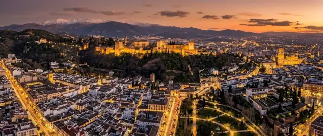 La Alhambra iluminada al atardecer sobre Granada, con Sierra Nevada al fondo