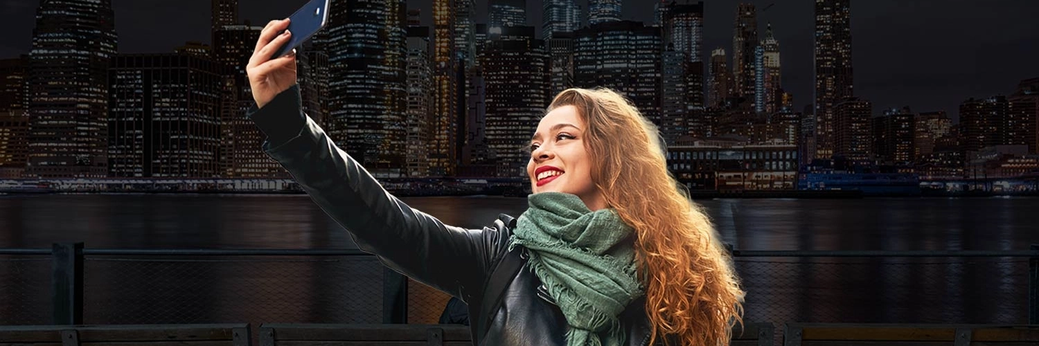 A secure and welcoming overhead view of a woman safely taking a selfie in busy New York City.