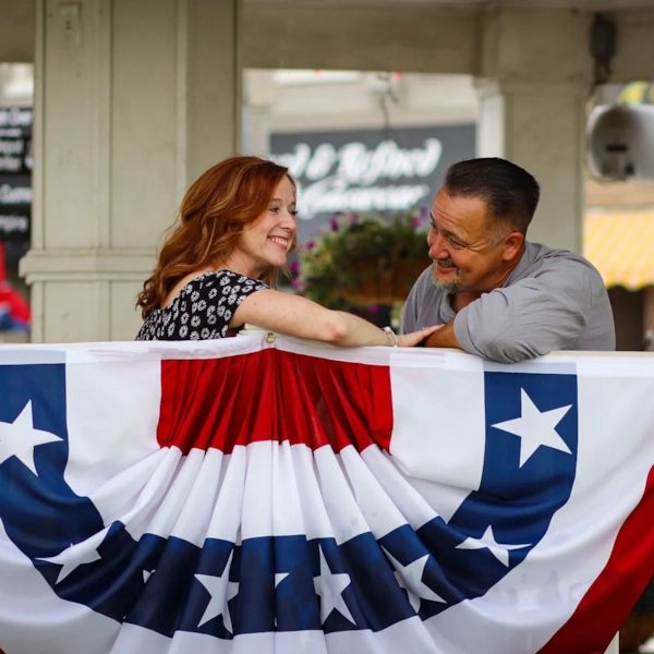Illustrative photo, not an actual member. A couple at a community fair with patriotic bunting.