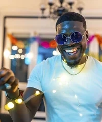 A man in sunglasses laughing at a party with fairy lights