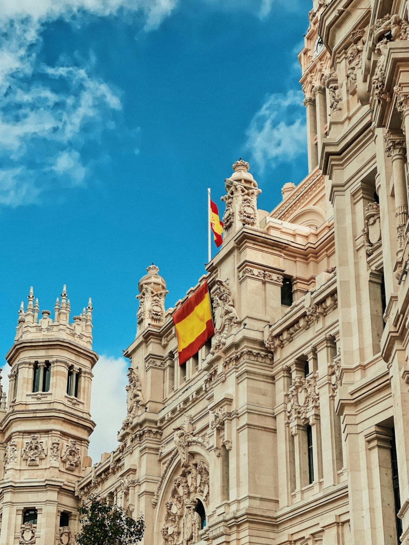 El Palacio de Cibeles, en Madrid, con banderas de España bajo un cielo azul