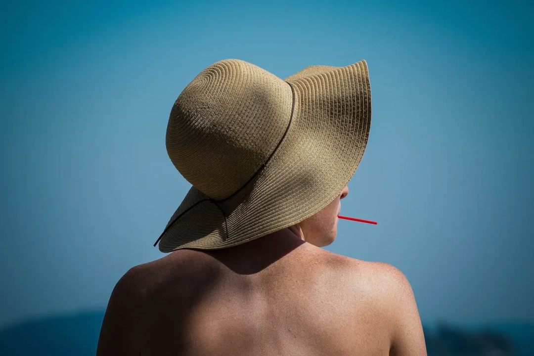 Illustrative stock photograph of an adult wearing a sunhat beside the sea