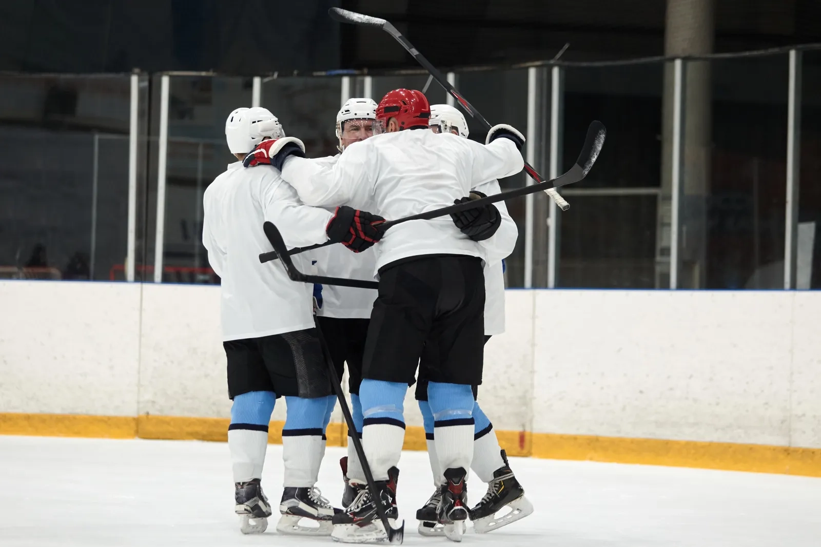 Hockey players in white jerseys celebrating together on the ice