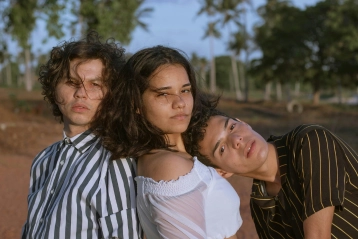 A happy throuple holding hands in nature