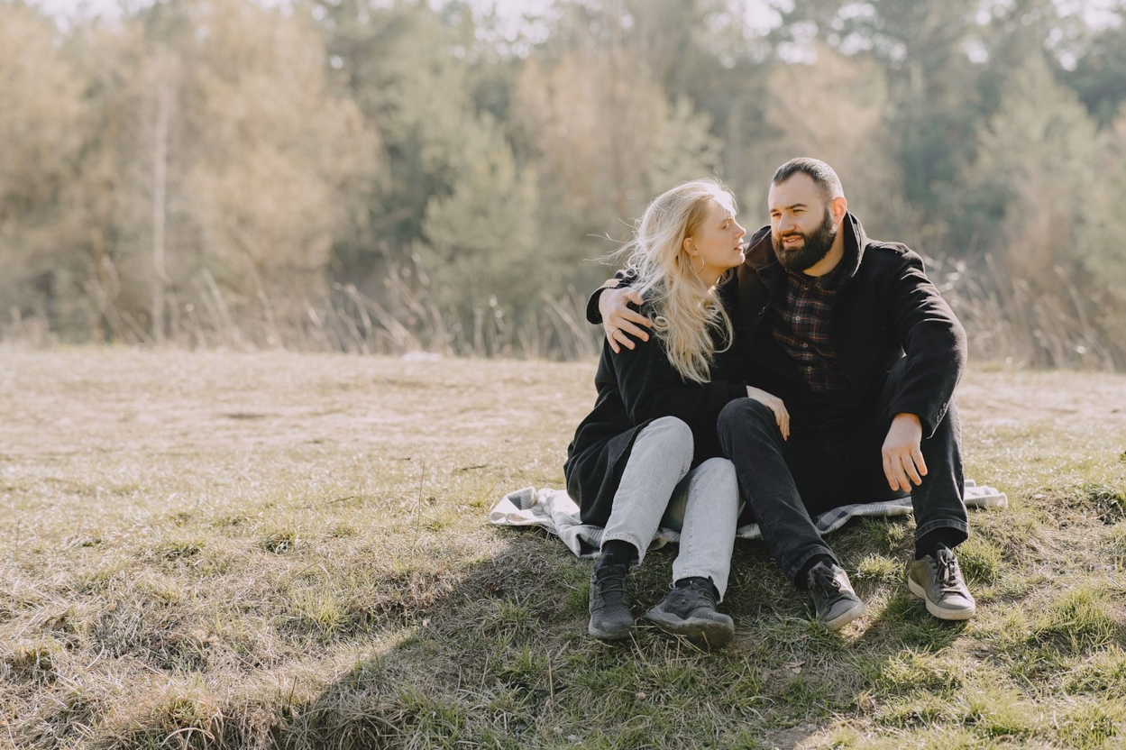 Couple sitting close together on a blanket in a grassy field