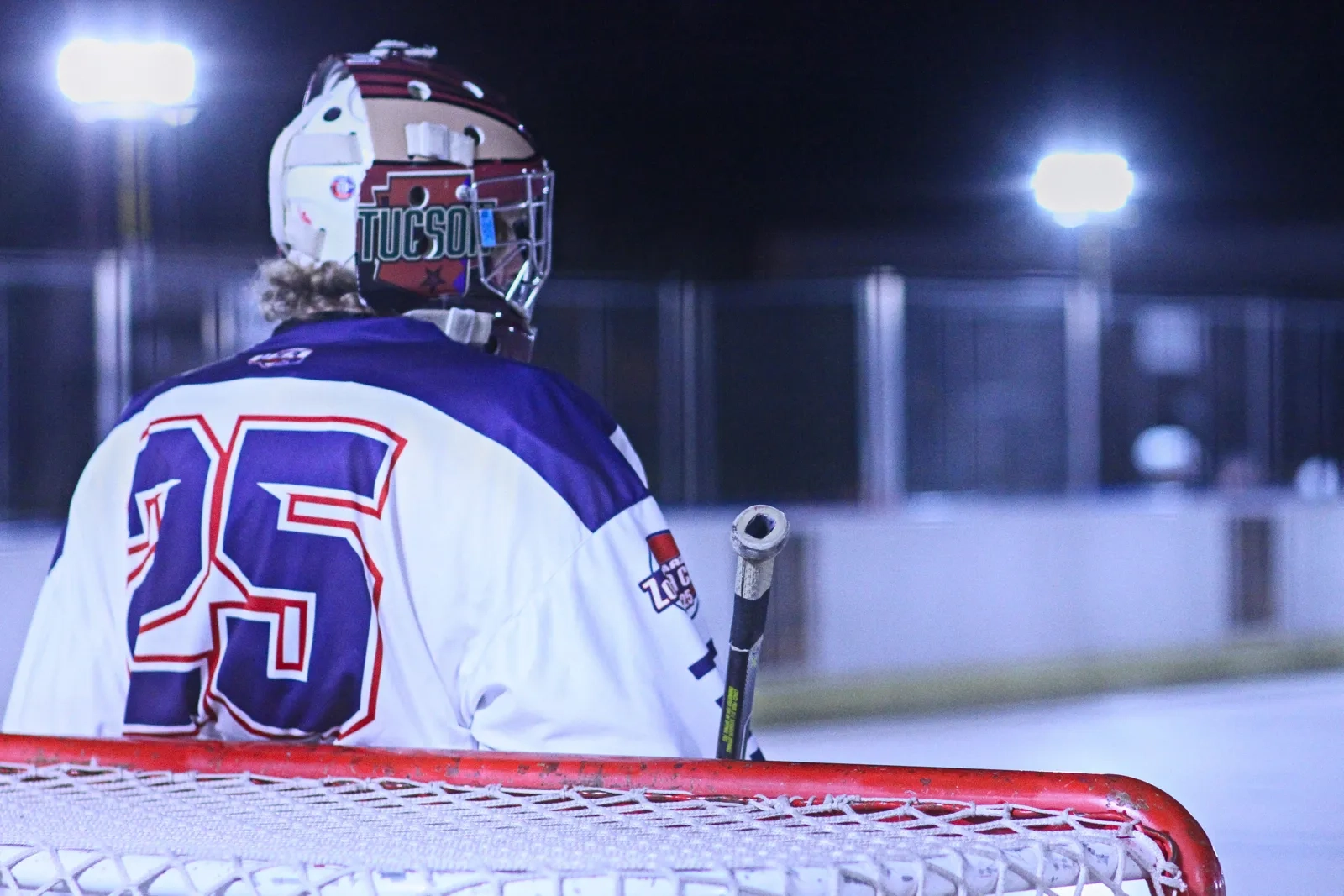 A goalie standing under bright arena lights