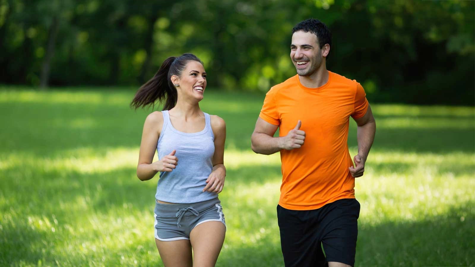 A smiling couple jogging together through a park, active singles in Pennsylvania