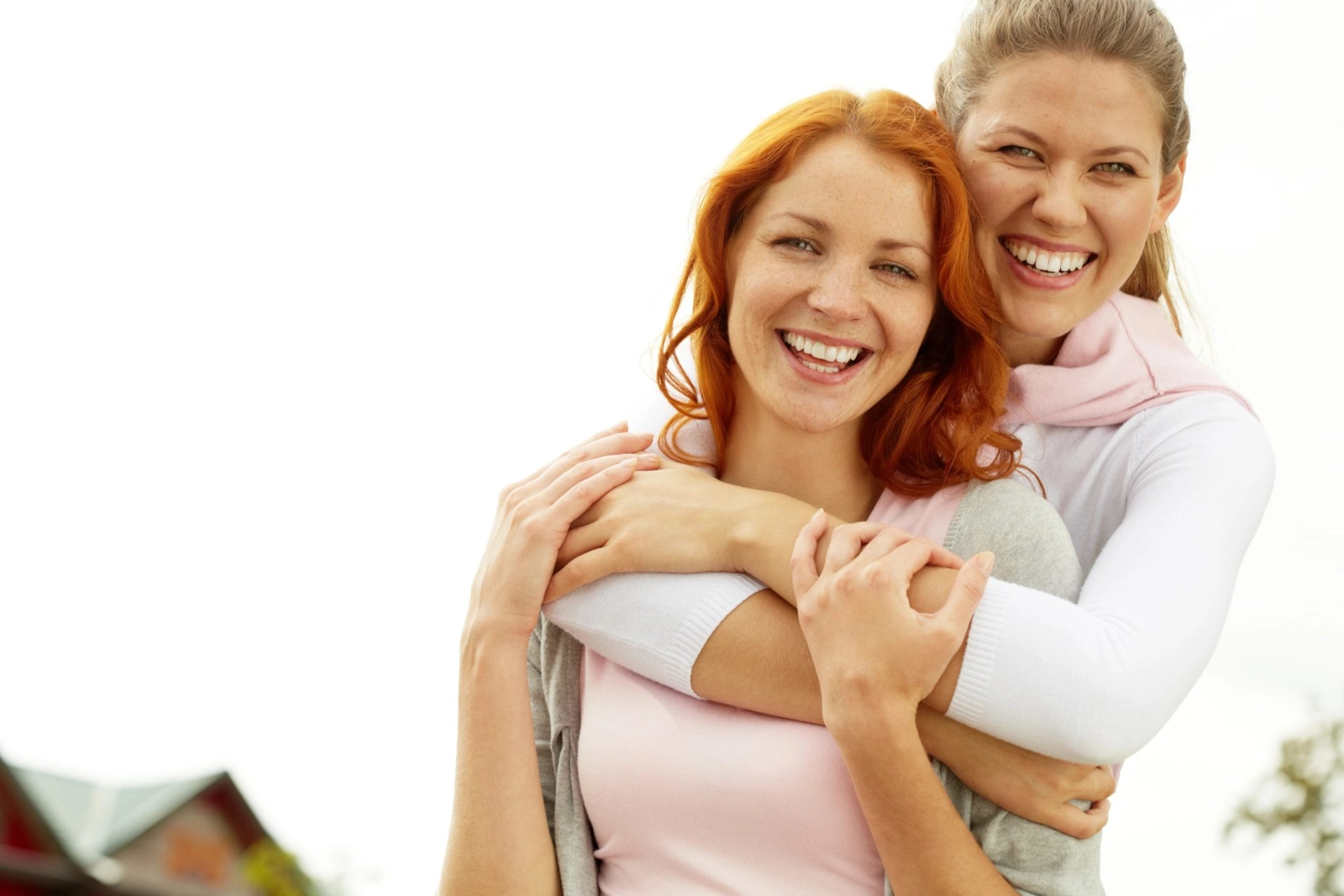 A woman hugging her partner from behind, both of them laughing