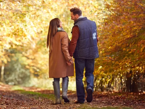 A couple walking away down an avenue of trees in full autumn colour