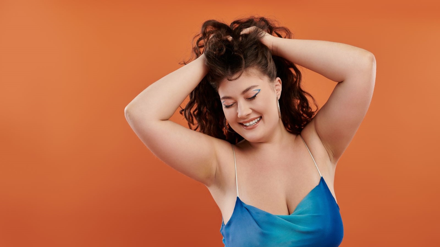A woman laughing and running her hands through her hair, feeling confident