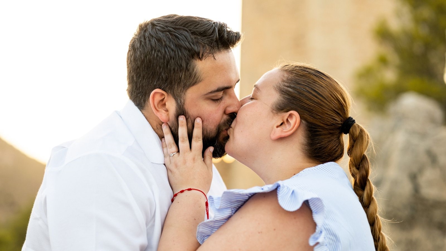 A couple sharing a kiss outdoors in golden light