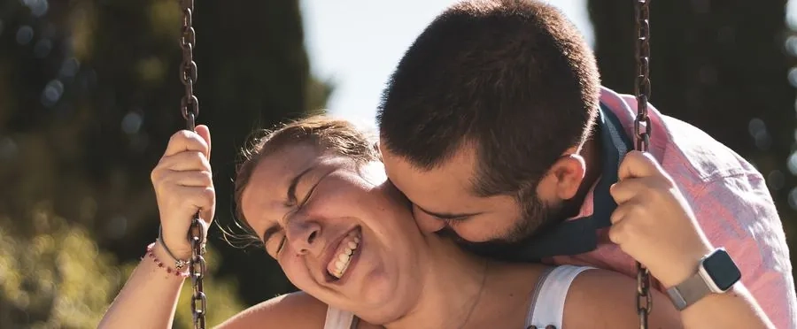 A laughing couple sharing a moment on a swing