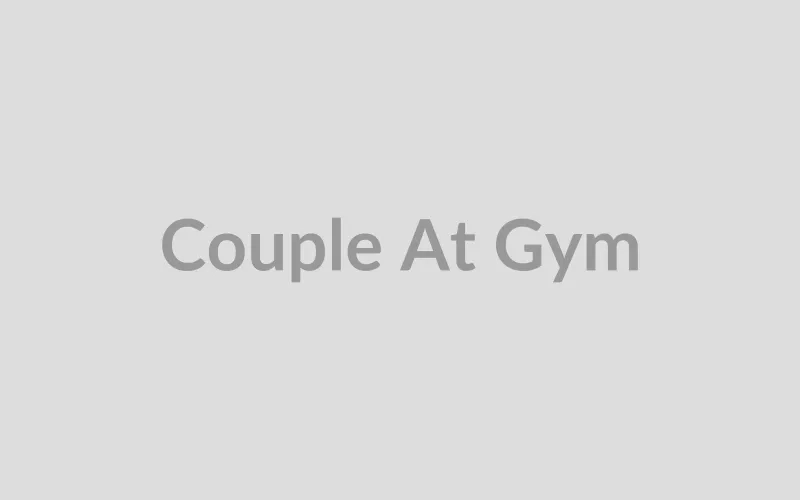 Fit couple working out together with dumbbells at gym