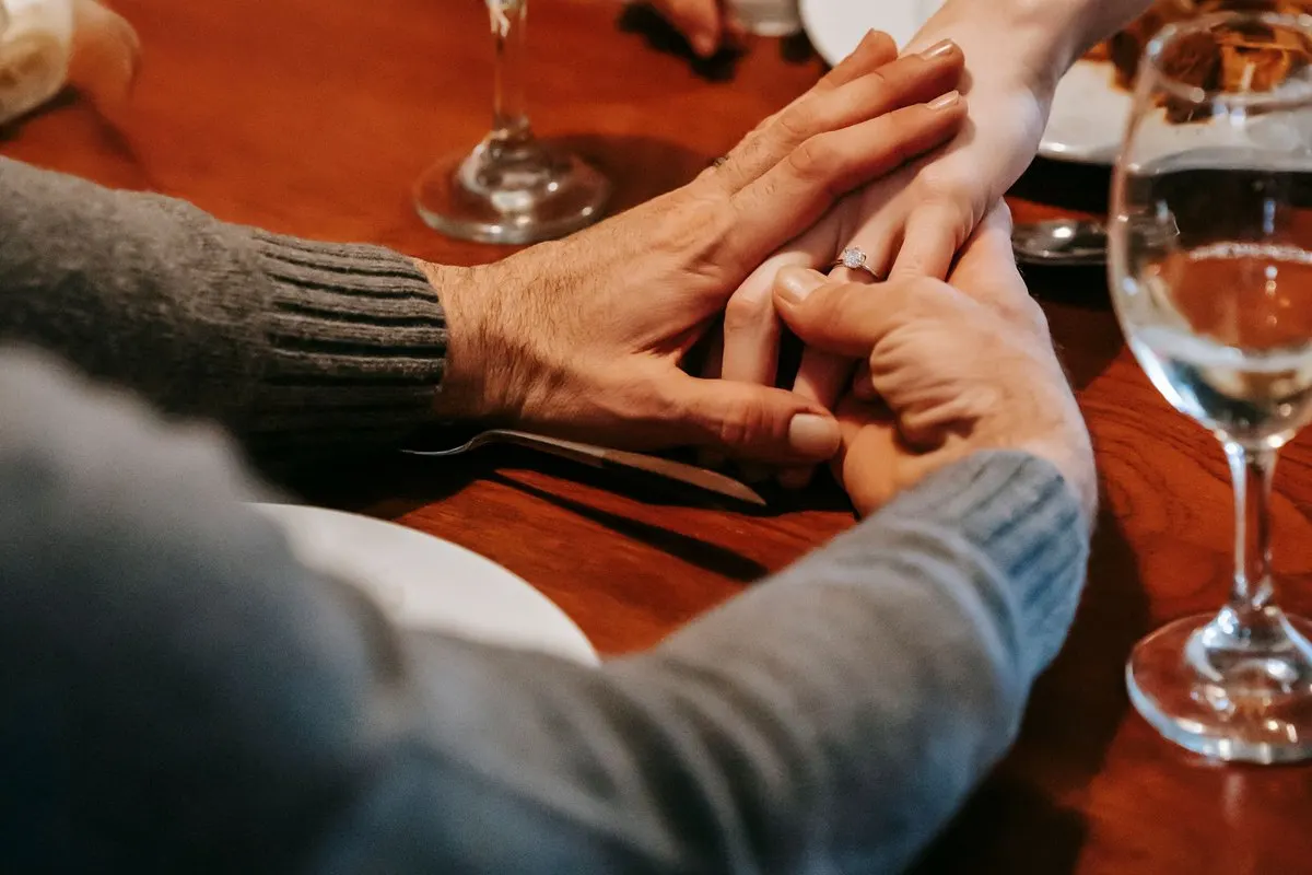 Hands resting together on a restaurant table between two glasses of white wine