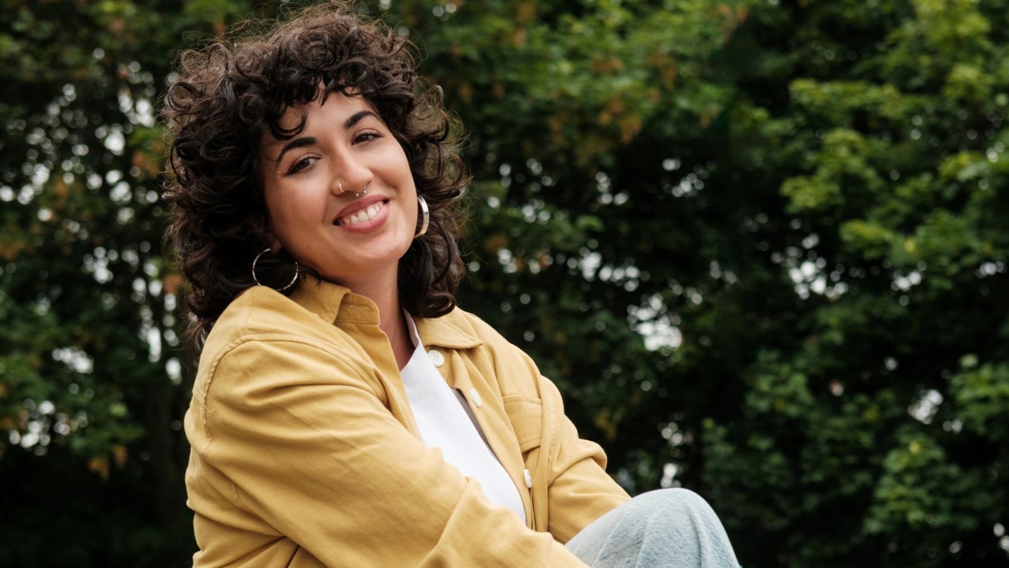 A woman sitting outdoors, smiling calmly