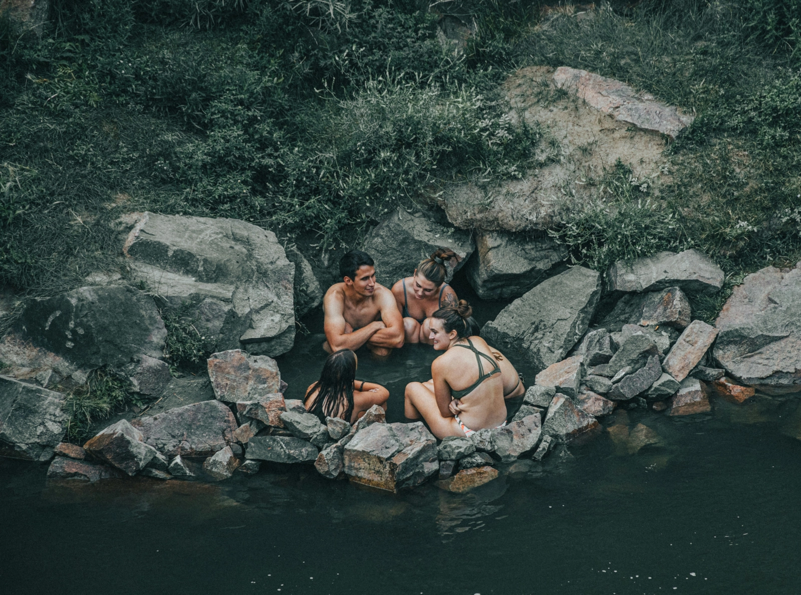 Grupo de personas relajadas juntas en una poza de agua natural