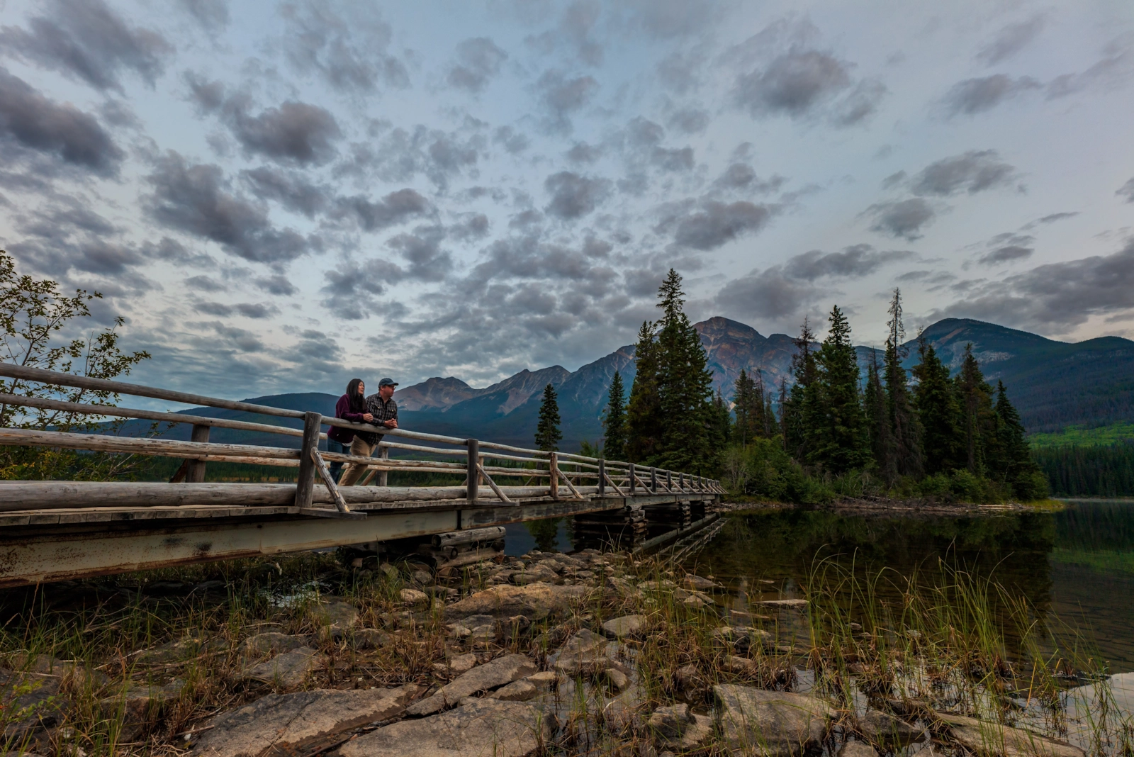 Boardwalk curving along a quiet mountain lake