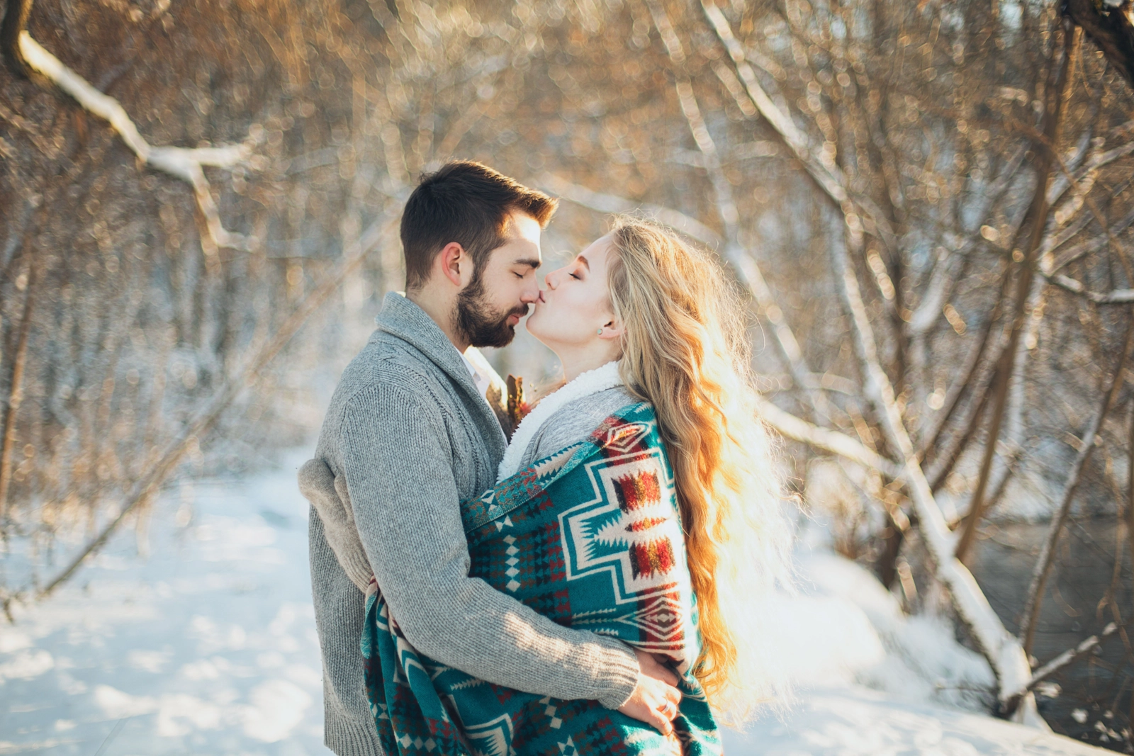 Couple enlacé lors d'une promenade dans un boisé enneigé