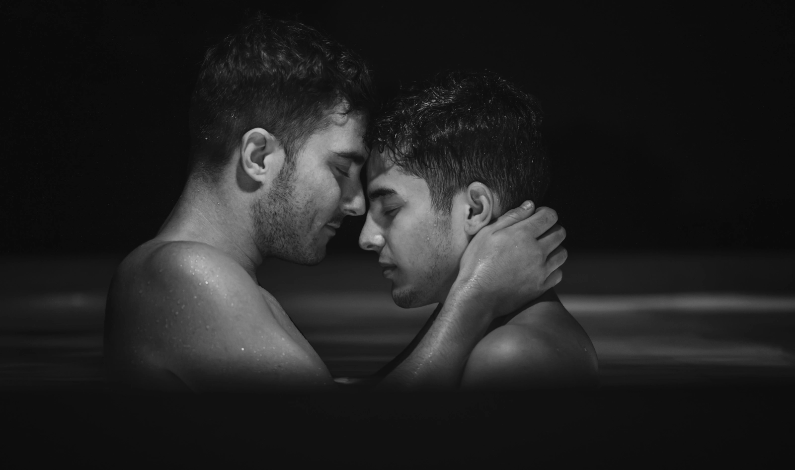 Dos hombres frente a frente en el agua, en blanco y negro.