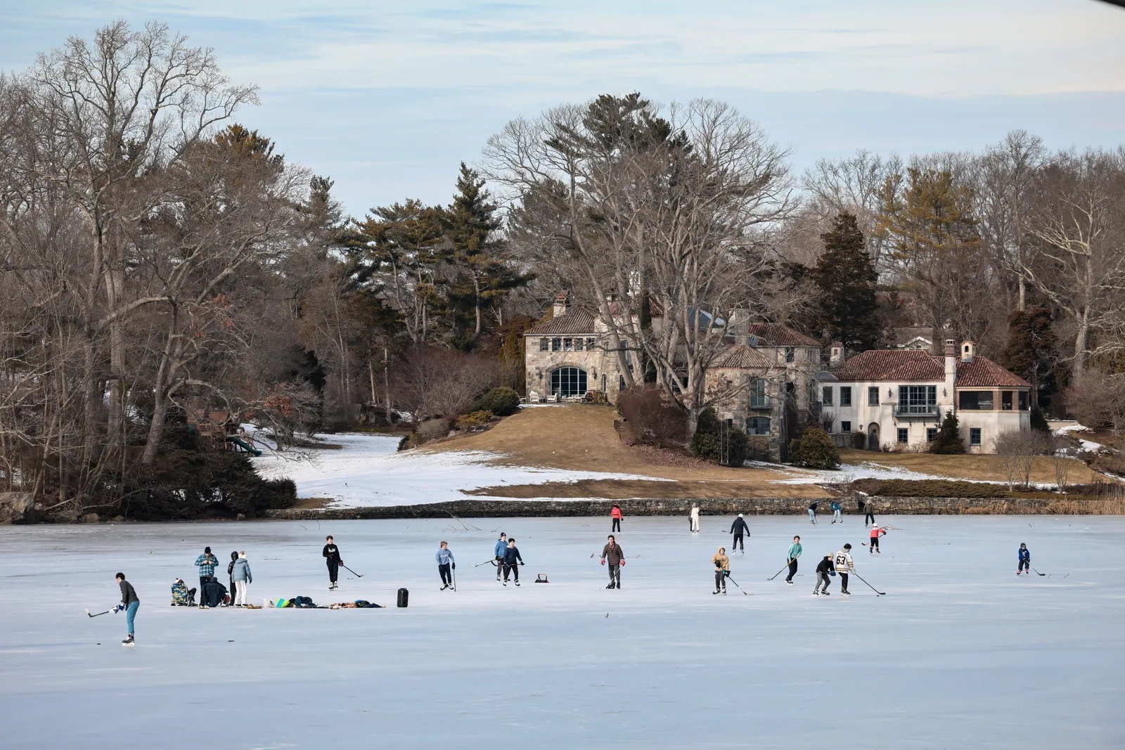 Skaters on a frozen lake surrounded by homes